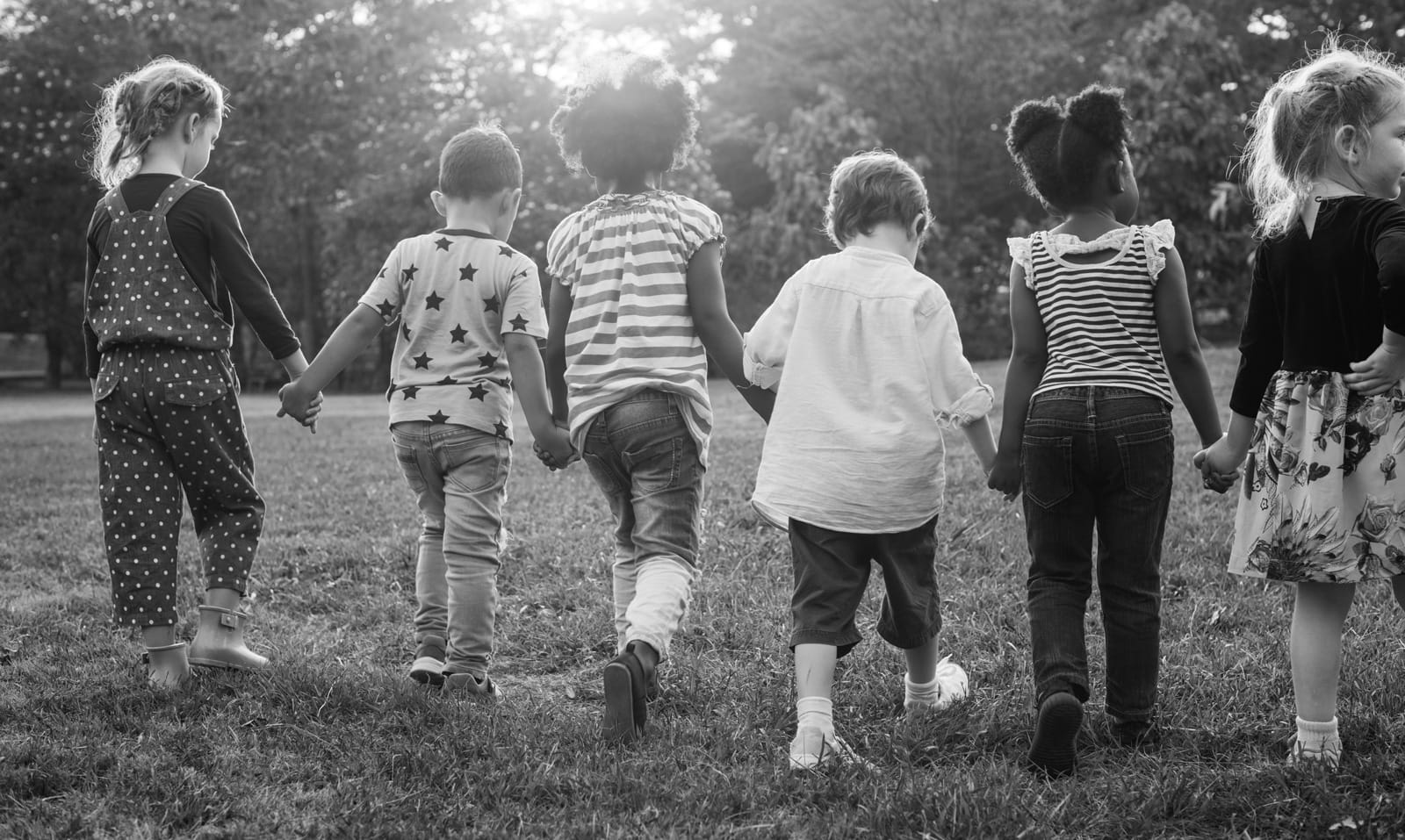A group of children holding hands walking in the park